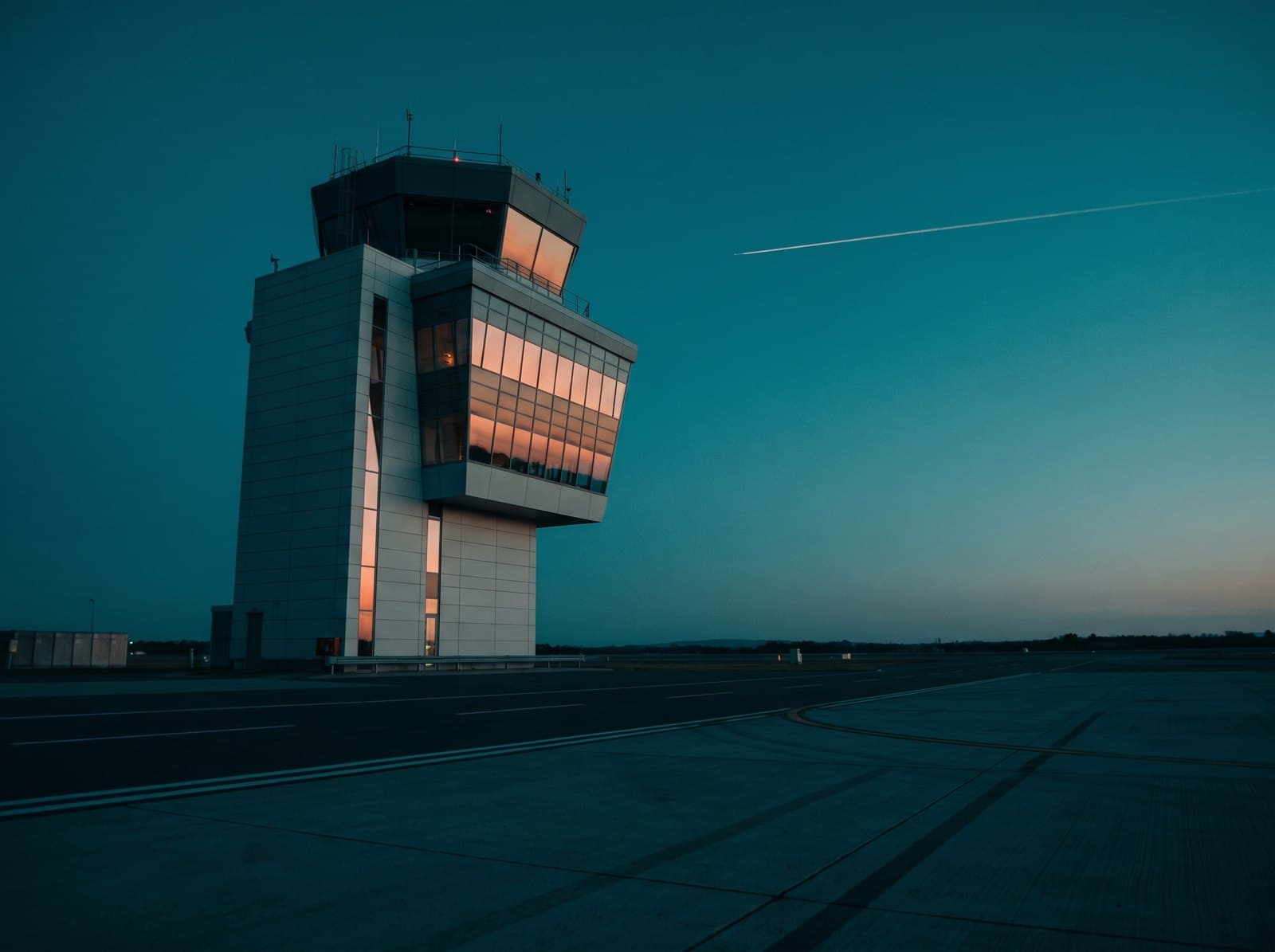 An airport control tower glowing at blue hour